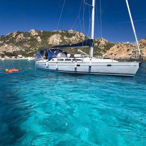 Baden, relaxen - im Hintergrund ein Segelschiff Segelyacht im klaren, türkisfarbigem Wasser mit Bergen im Hintergrund.