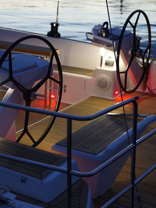 Zwei Steuerräder am Deck mit sanftem Licht auf einem Segelschiff, reflektierend im Wasser.